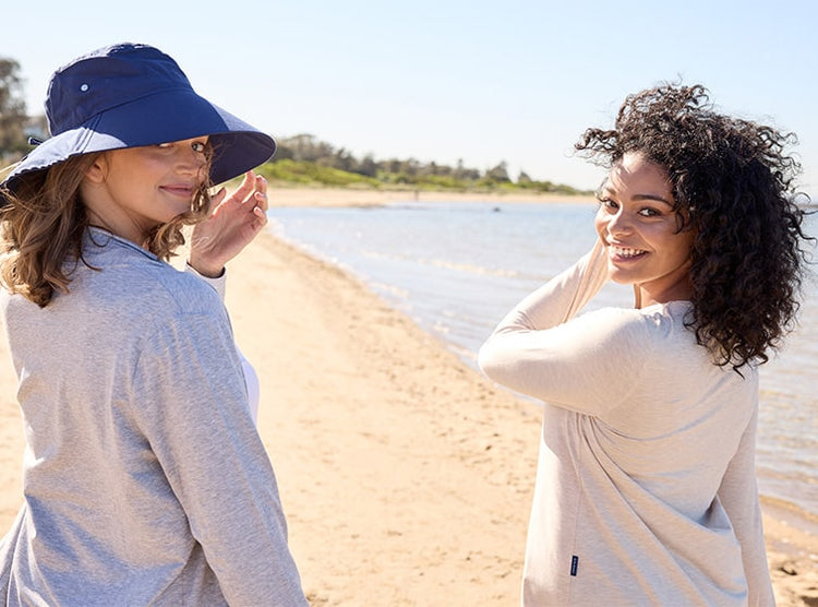 Women walking on the beach wearing Solbari sun hat and clothing