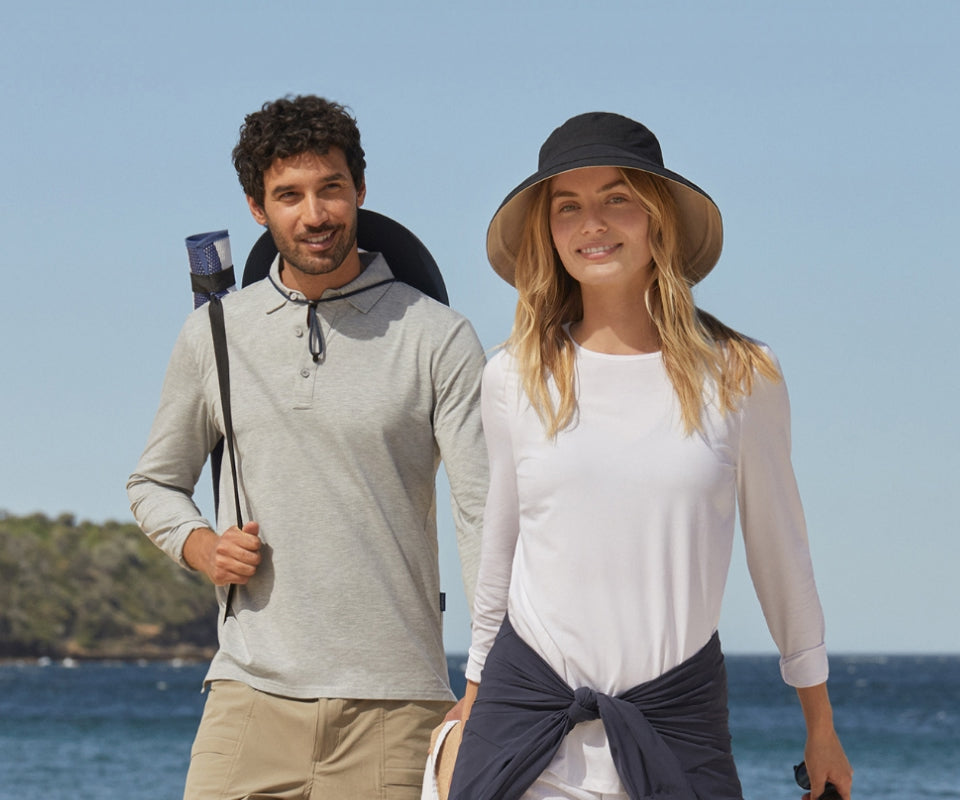 Man and woman standing on a beach with clear blue sky and ocean.