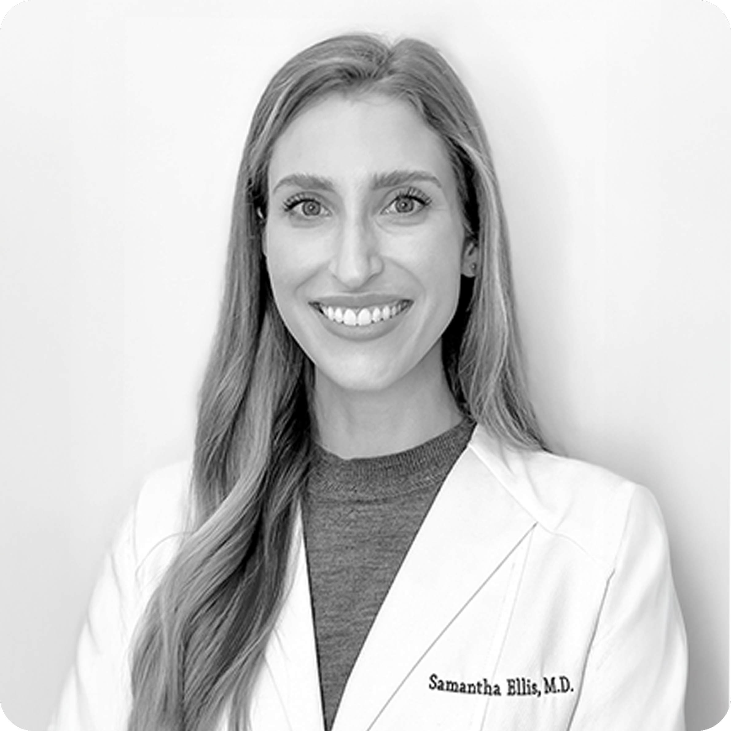 Black and white photo of a woman wearing a white lab coat with 'Samantha Ellis, M.D.' on it.